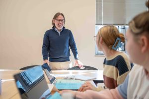 Dr. Ollie Dreon standing in a classroom with two students looking at him.
