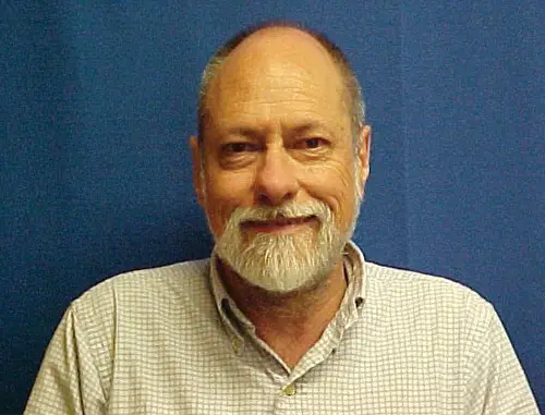 https://nationalmedals.org/expert/richard-mankin/ A close up of Richard Mankin with short grey hair and a short grey beard wearing a white shirt stood in front of a blue background